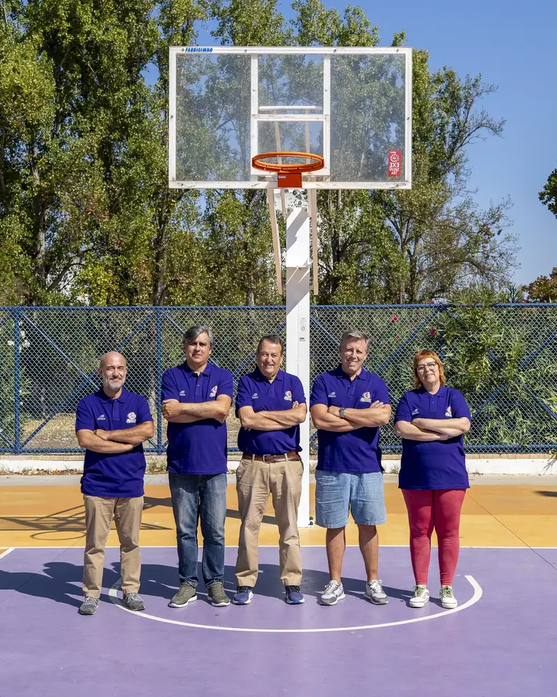 A equipa da Lista B, de braços cruzados, sob o cesto de um campo de basquetebol ao ar livre.